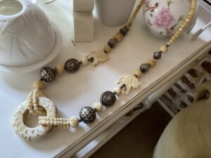 Ce collier est une traversée.Une ligne qui relie les origines à aujourd’hui.
Un bijou qui ne se contente pas d’être porté — il s’incarne.
Le Cercle des Origines s’articule autour d’un pendentif central sculpté, forme pleine, presque rituelle.
Autour de lui, des perles, des volumes, des éléments gravés.
Certains évoquent des symboles.
D’autres des fragments de mémoire.